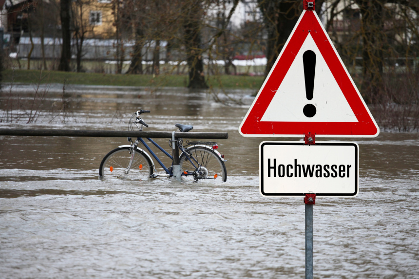 Fahrrad steht unter Wasser, Schild warnt vor Hoochwasser