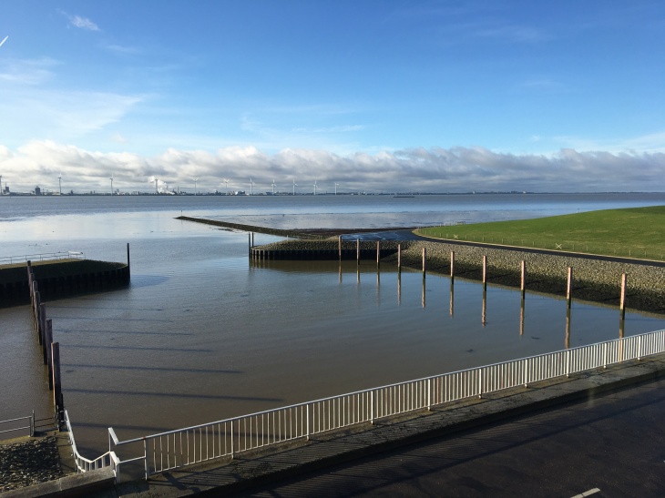 Das Siel und Schöpfwerk Knock in Emden. Es entwässert ein rund 35.000 Hektar großes Gebiet über das Knockster Tief in die Ems. Foto: Helge Bormann/Jade HS) Ein Wasserrückhaltebecken an der Nordsee mit Absperrgittern und Zugang zur Emsmündung